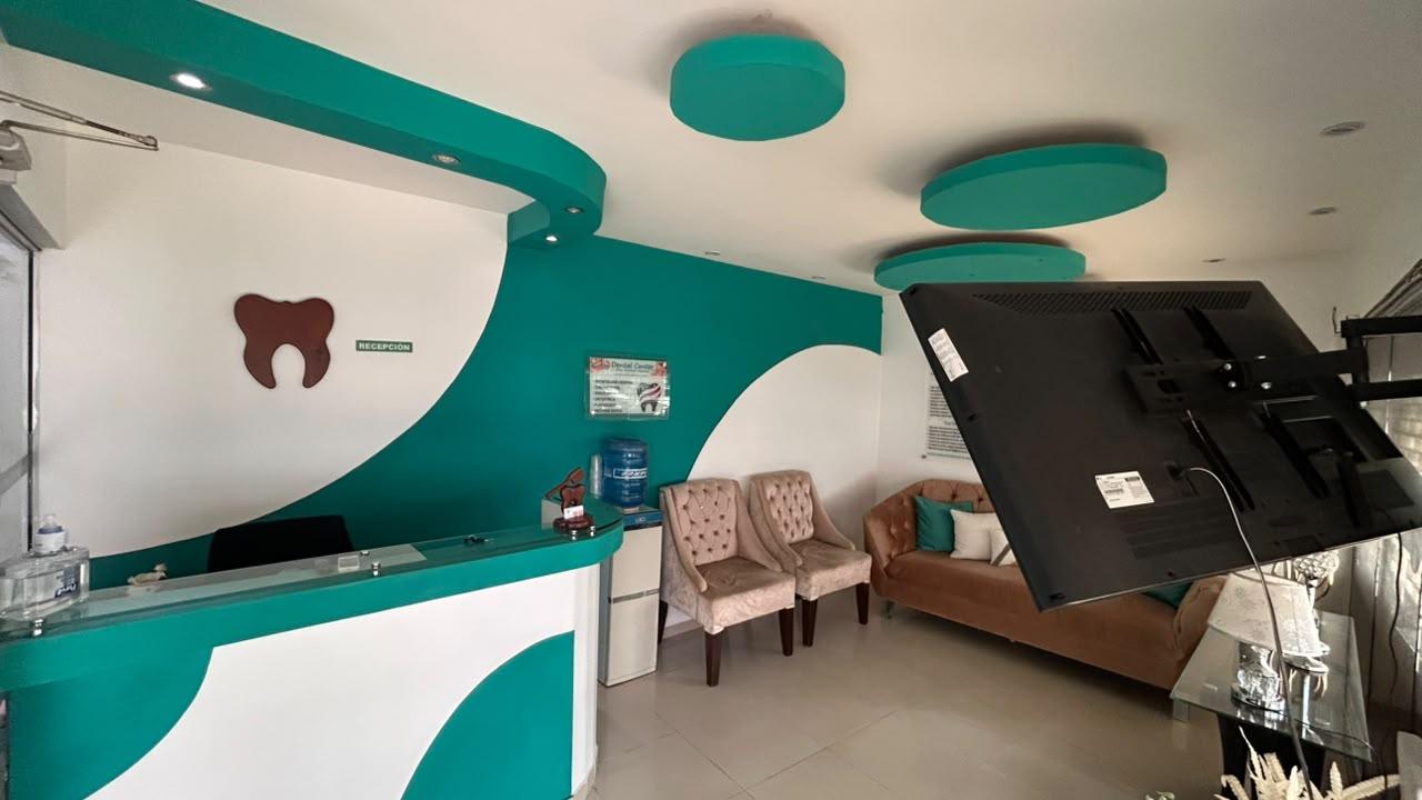 Recepción de Dental Center con la pared verde azulado, el mostrador y la sala de espera